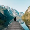 a person sitting on wooden planks across the lake scenery